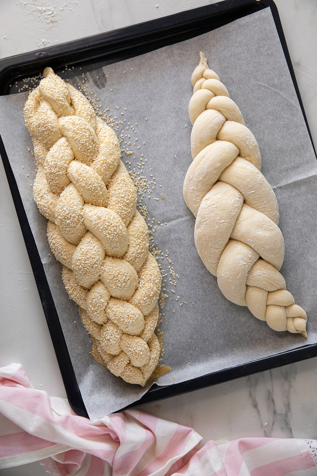 Perfect Challah. A 3-strand challah dusted with a fine layer of flour and a 6-strand challah brushed with egg yolk, water and maple and finished with sesame seeds. Photo: Tal Sivan-Ziporin